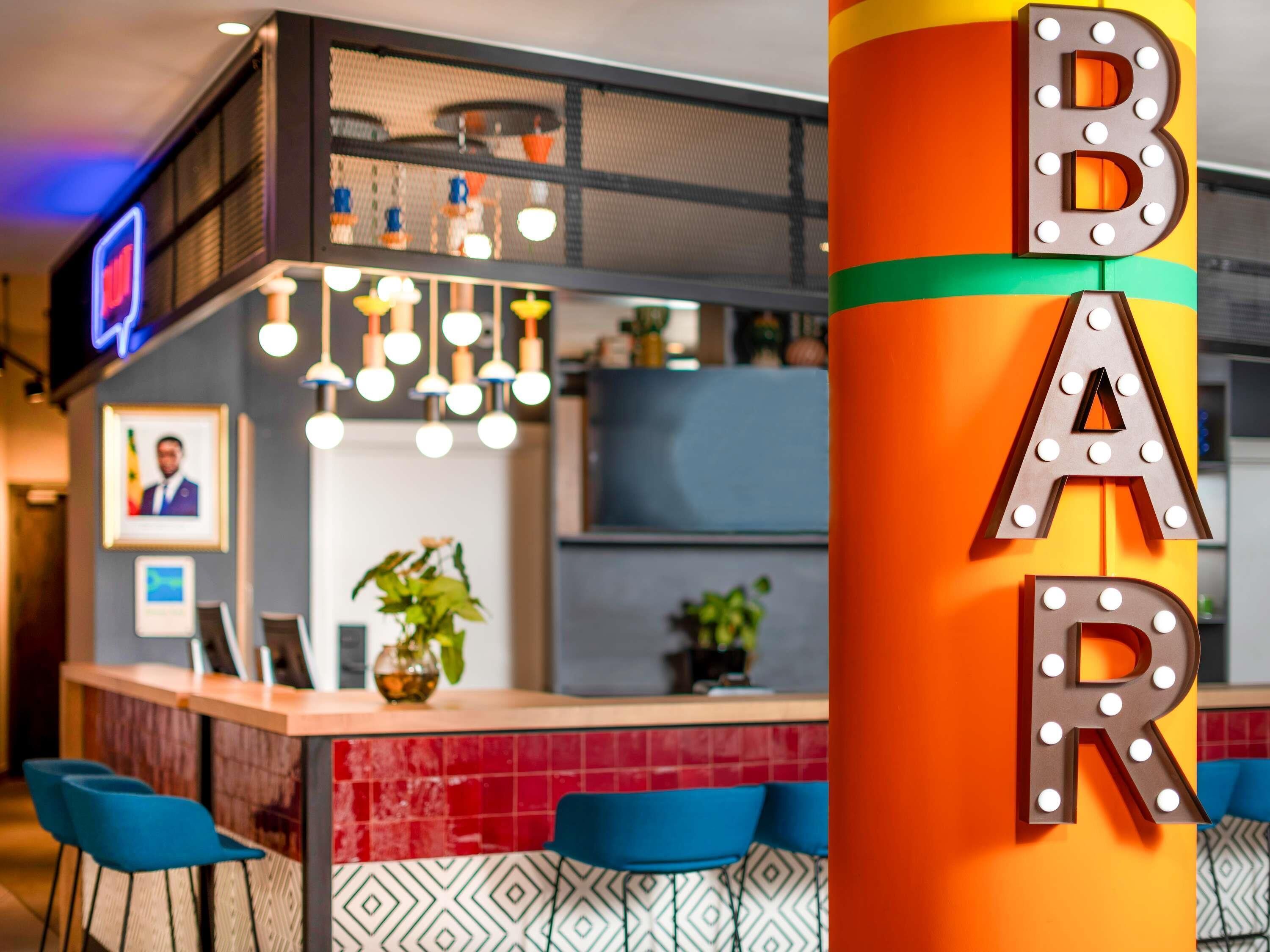 Un área de bar con un pilar colorido que dice "BAR" y sillas azules.