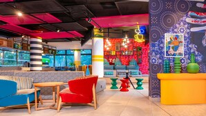 Un área de lounge moderna con asientos, una barra y un mural de pared colorido.
