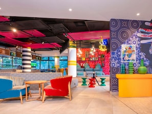 Un área de lounge moderna con asientos, una barra y un mural de pared colorido.