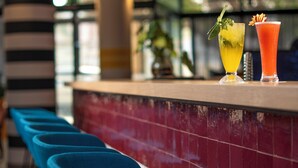 Una zona de bar con un mostrador de baldosas rojas, taburetes azules y dos bebidas.