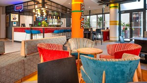 Zona de bar moderna con un letrero de neón, asientos coloridos y una barra con diferentes botellas.