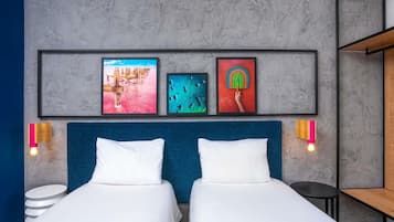 A hotel room with two beds, a large window, and artwork on the wall.