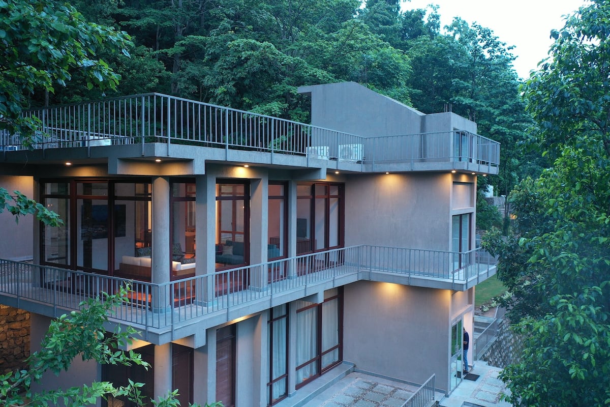 A modern multi-story building with balconies, large windows, and a stone base.