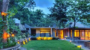 A modern house with a stone staircase, a well-maintained lawn, and outdoor lighting.