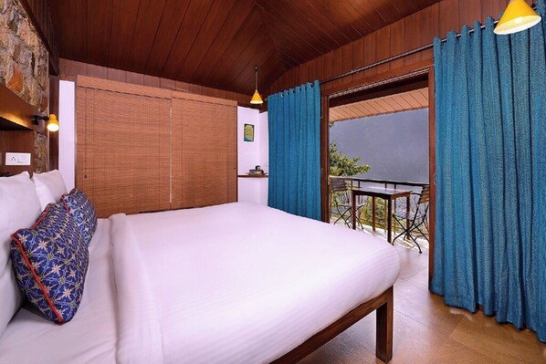 A bedroom with a large bed, a wooden ceiling, and a view of the outdoors.