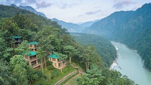 A hillside hotel with multiple buildings, a river, and lush greenery.