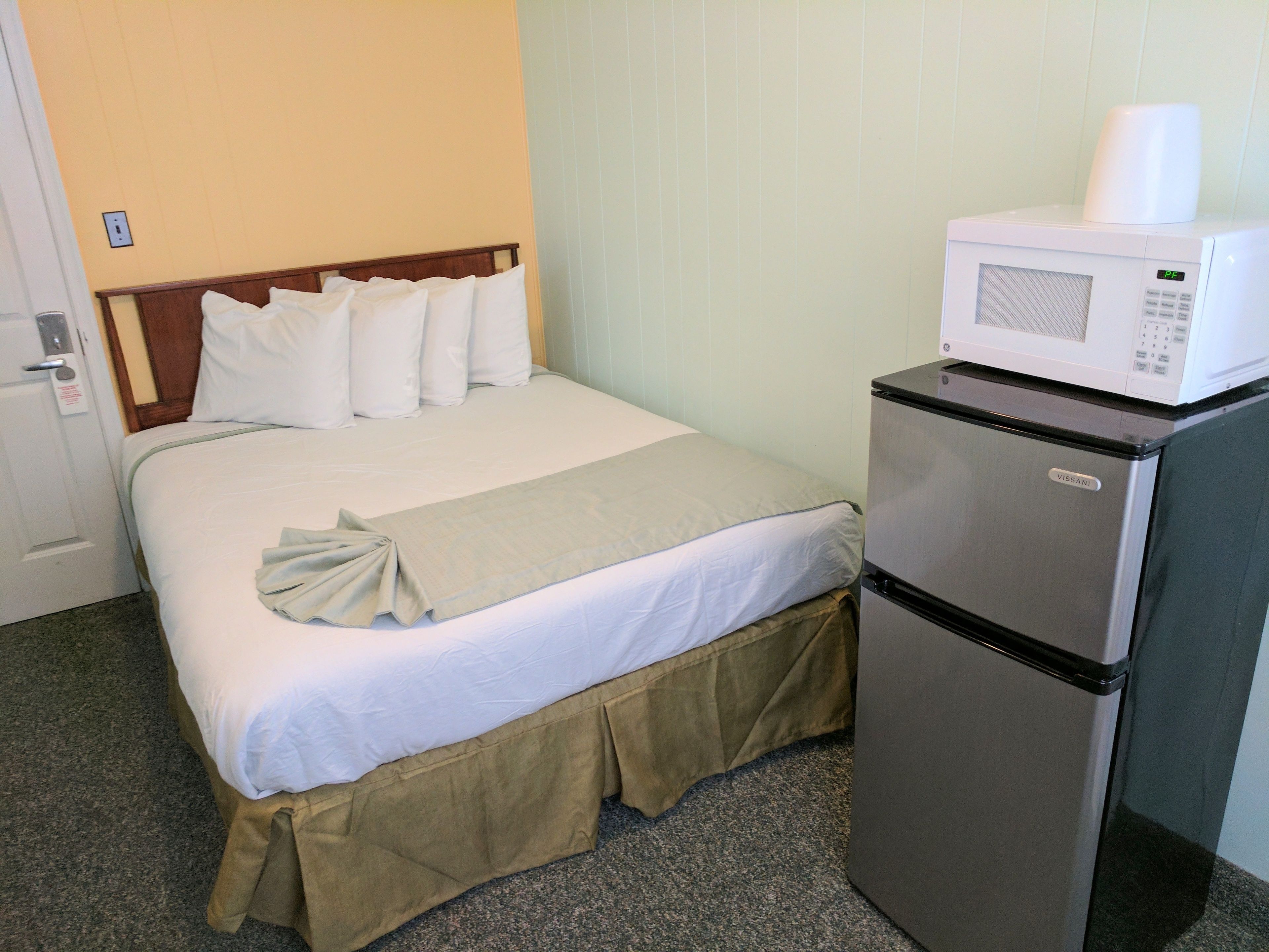 Quarto de hotel com cama, minibar e micro-ondas.