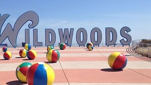 A beach area with large letters spelling "Wildwoods" and several colorful beach balls.