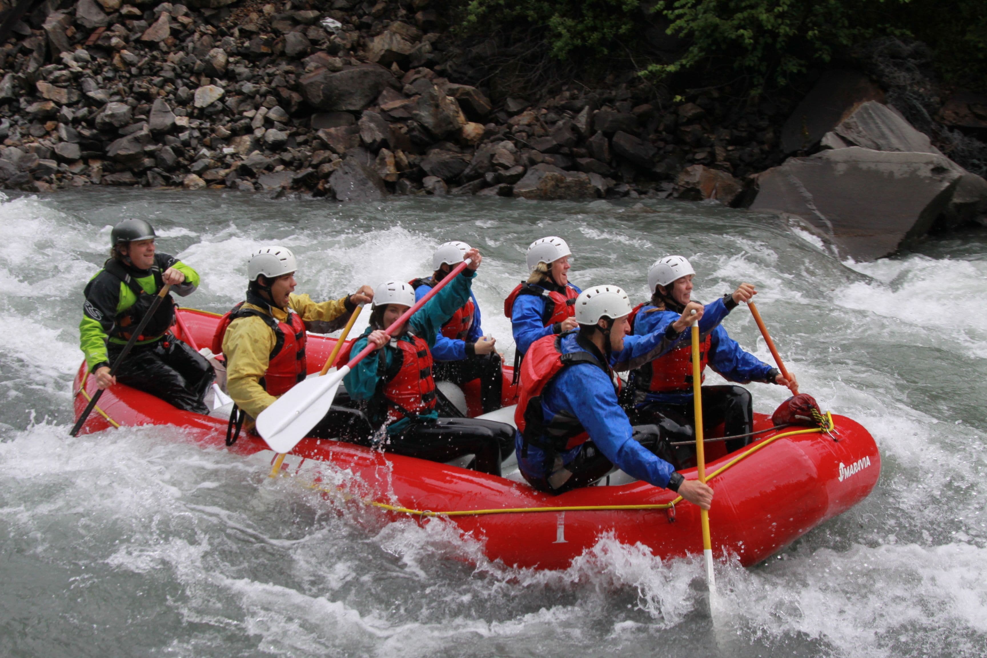 Eine Gruppe von Menschen in einem roten Luftboot auf einem Fluss unterwegs.