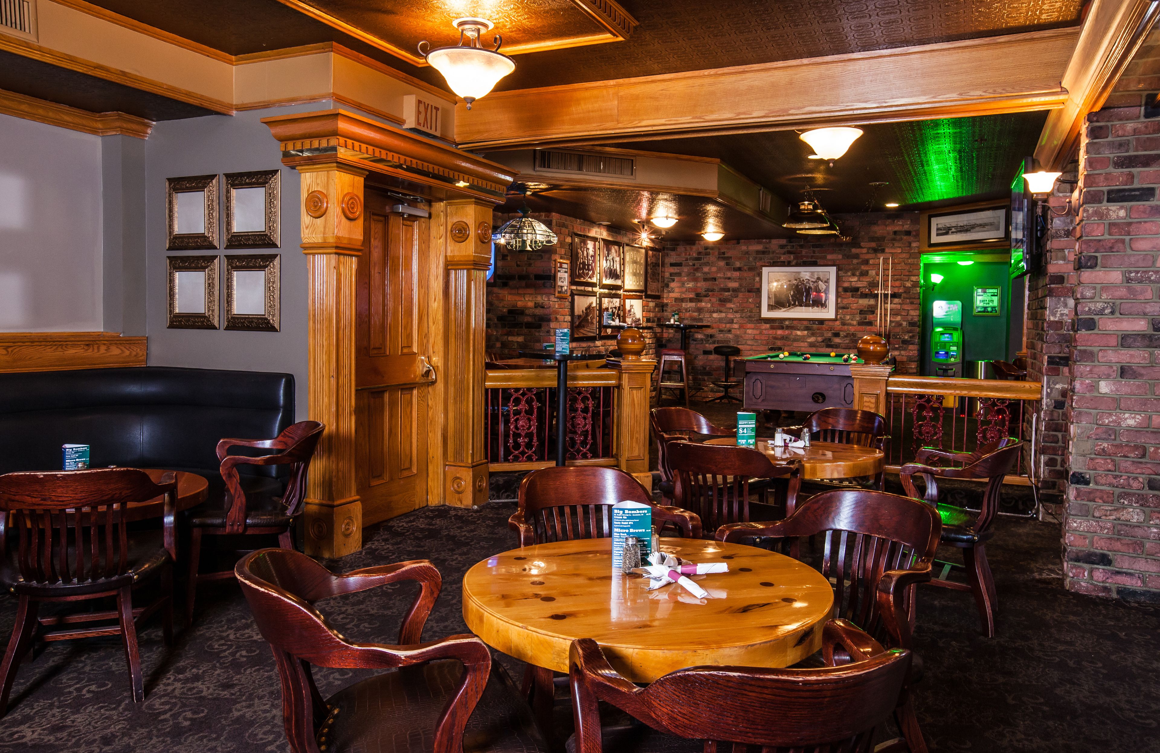 A bar area with wooden furniture, a billiards table, and a green machine, likely a cash register or point of sale system.