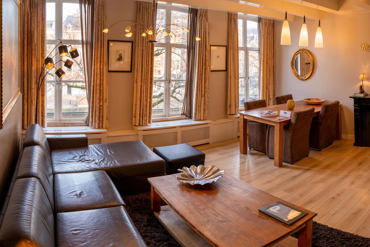 Una sala de estar moderna con un sofá, una mesa de centro de madera y un comedor con sillas y una mesa.
