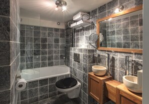 Een badkamer met een bad, toilet en twee wasbakken.