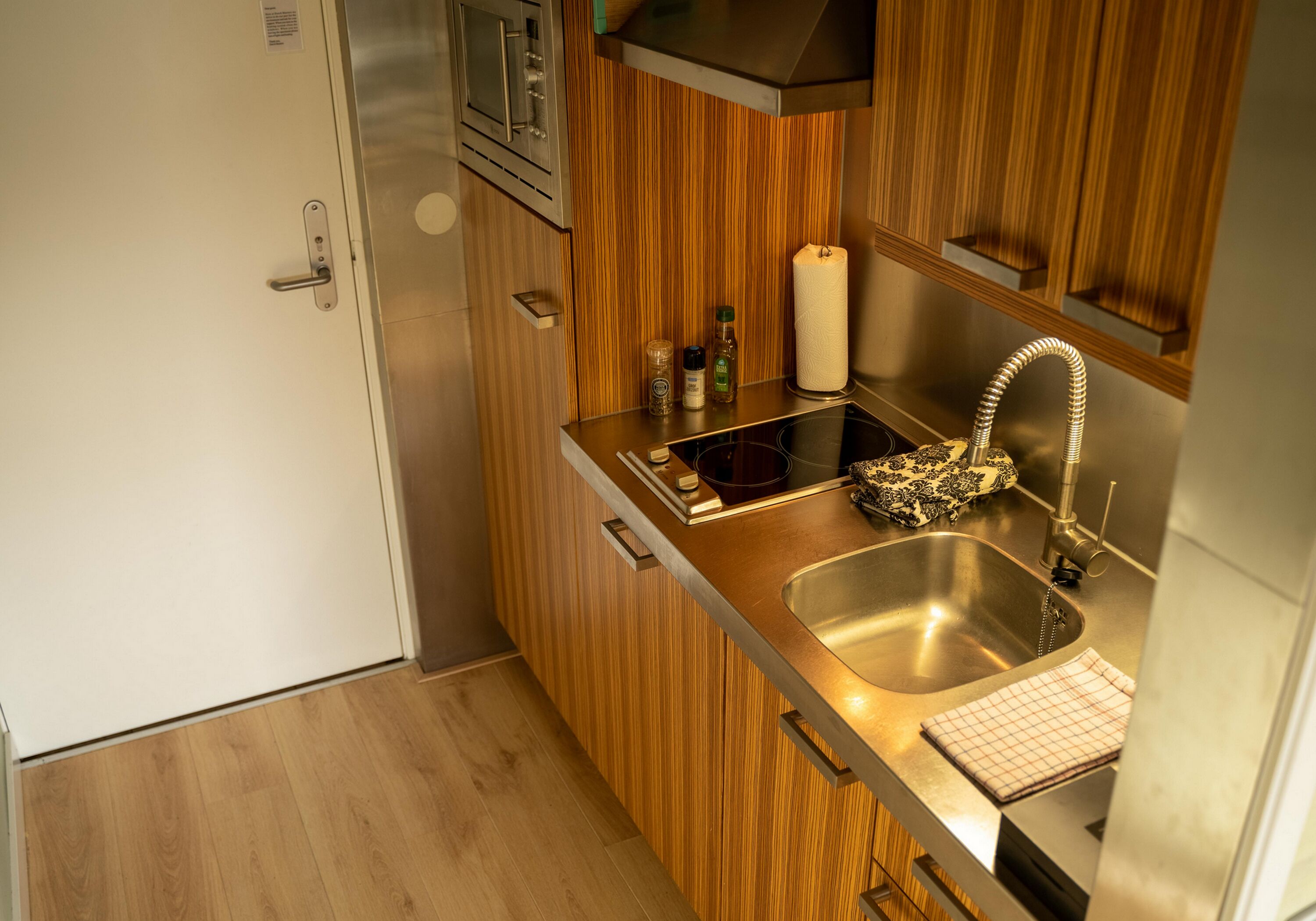 A compact kitchen with wooden cabinets, a stainless steel sink, and a built-in oven.