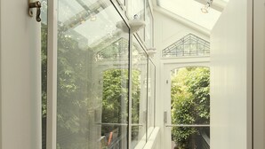 A conservatory with glass walls and a white interior, offering views of lush greenery outside. - Dutch Masters Amsterdam (Amsterdam)