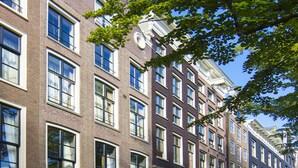 A row of historic brick buildings with large windows and a clear blue sky. - Dutch Masters Amsterdam (Amsterdam)