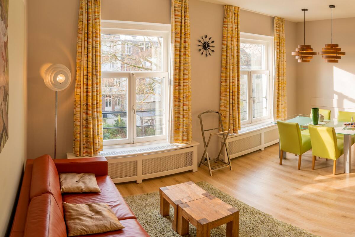 Una sala de estar con un sofá rojo, una mesa de centro de madera y un comedor con sillas verdes.