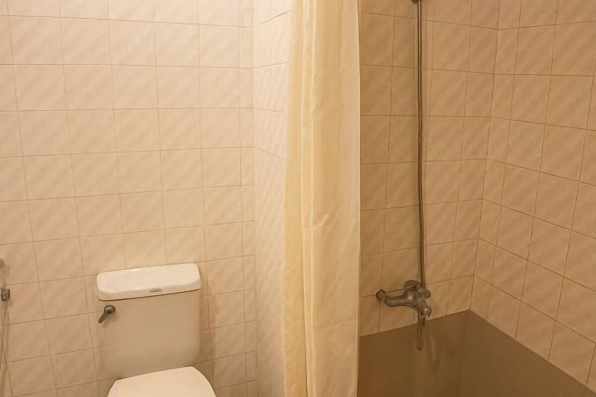 A bathroom with a toilet, a shower, and a tiled wall.