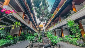 A courtyard with a central statue, surrounded by lush greenery and potted plants. - Bali Summer Hotel (Kuta)