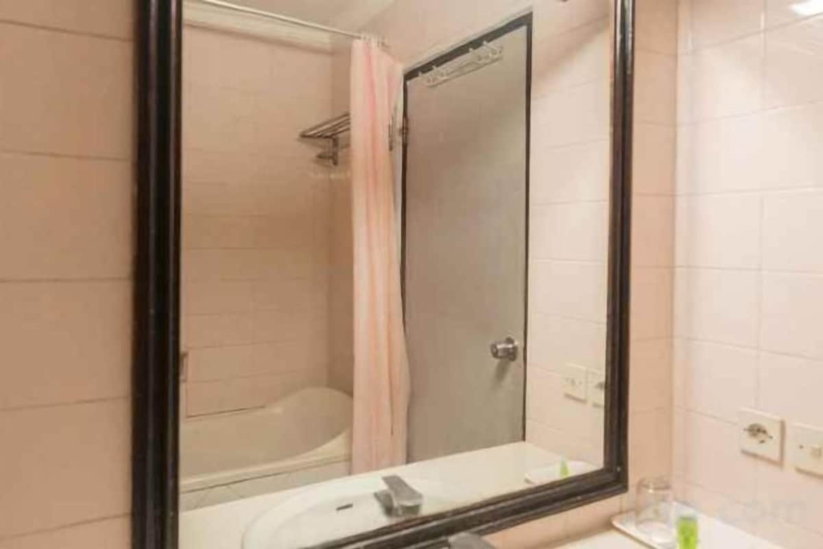 A bathroom with a bathtub, a mirror, and a sink.