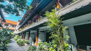 A traditional building with a covered walkway, potted plants, and a clear blue sky. - Bali Summer Hotel (Kuta)