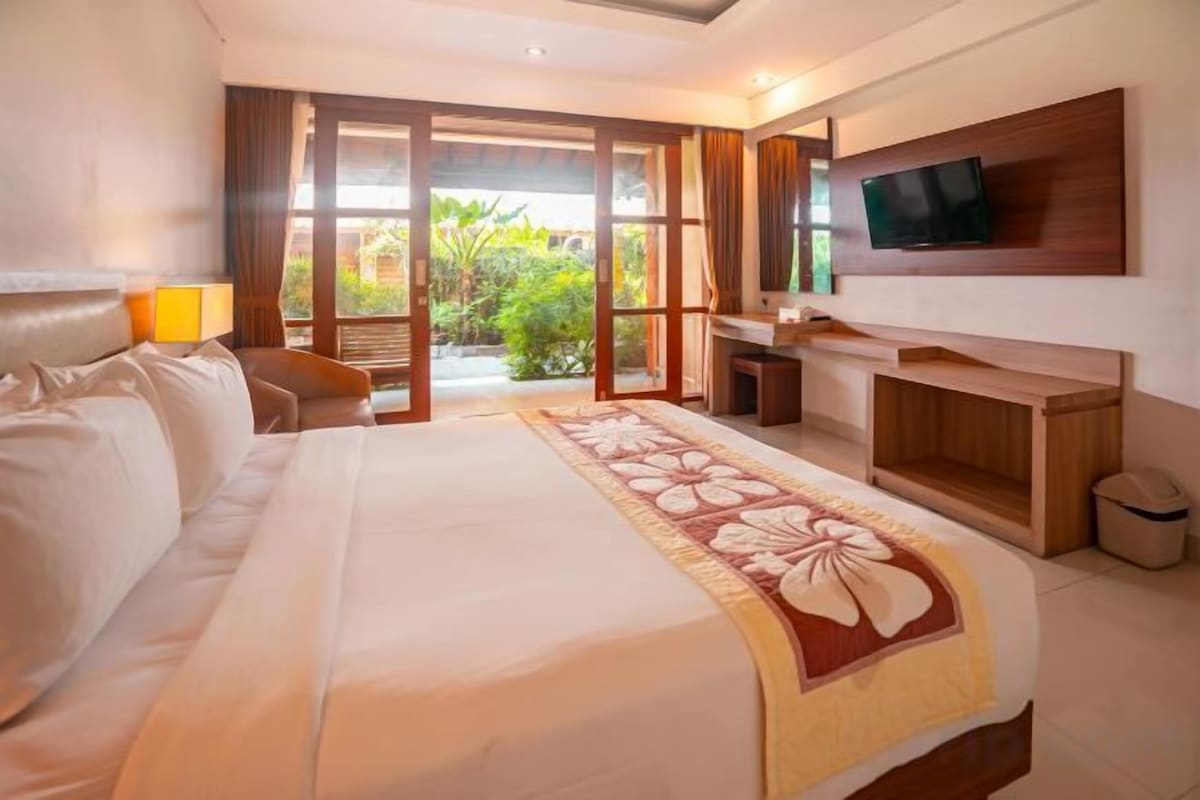 A hotel room with a large bed, a desk, a TV, and a view of the outdoors.