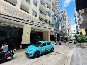 A hotel with a prominent entrance, a blue car parked in front, and a pedestrian walkway. - Victorian Nha Trang Hotel (Nha Trang)