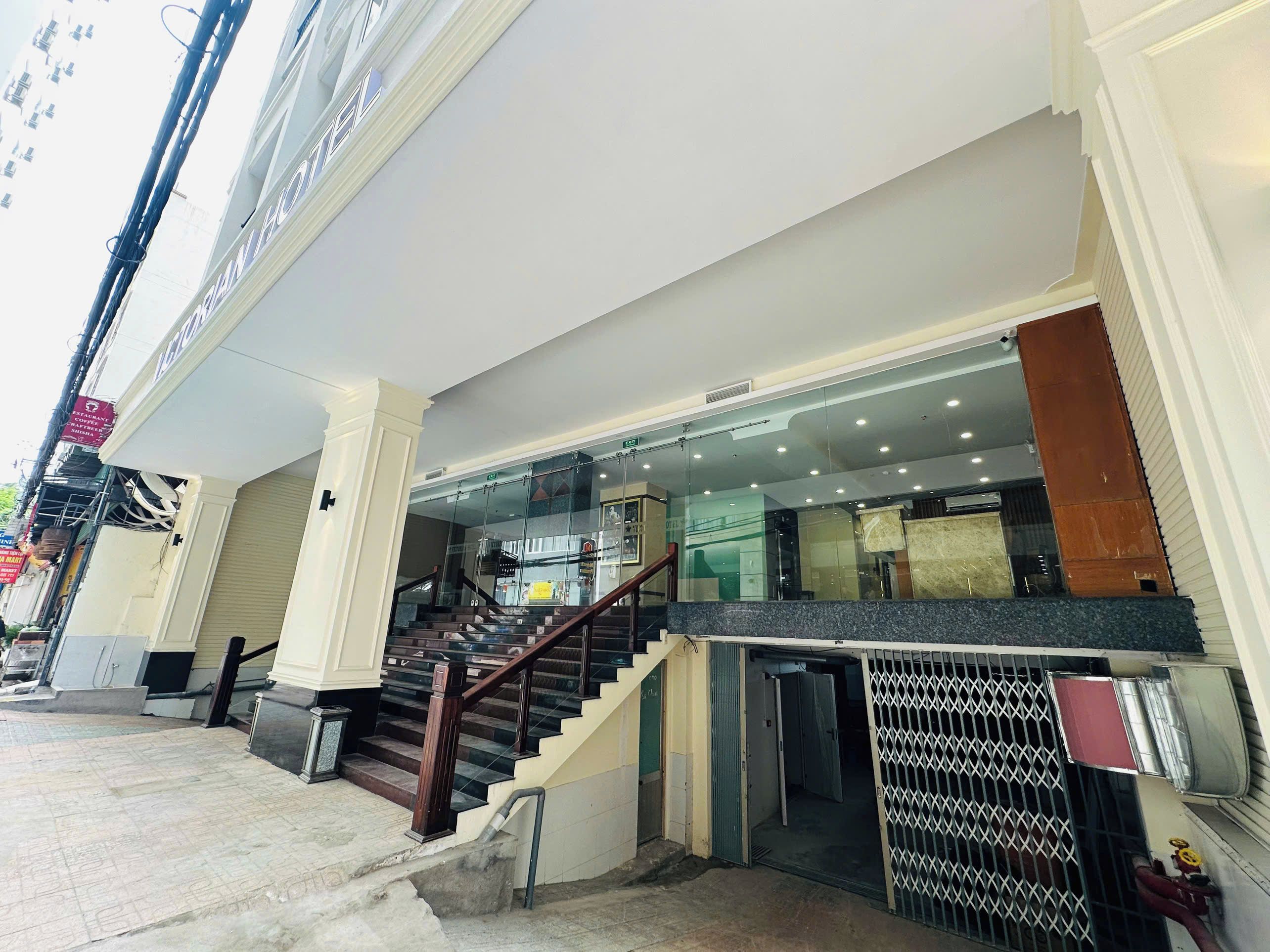 A hotel entrance with a staircase leading to the lobby, a glass door entrance, and a metal gate.