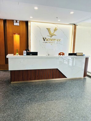 A reception desk at the NHA Trang Hotel with a marble top, a logo, and a reception sign. - Victorian Nha Trang Hotel (Nha Trang)