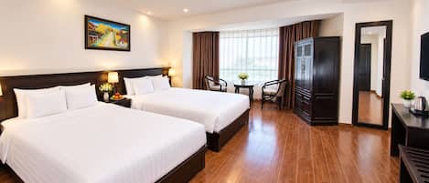 A hotel room with two beds, a desk, a chair, a TV, and a painting on the wall.