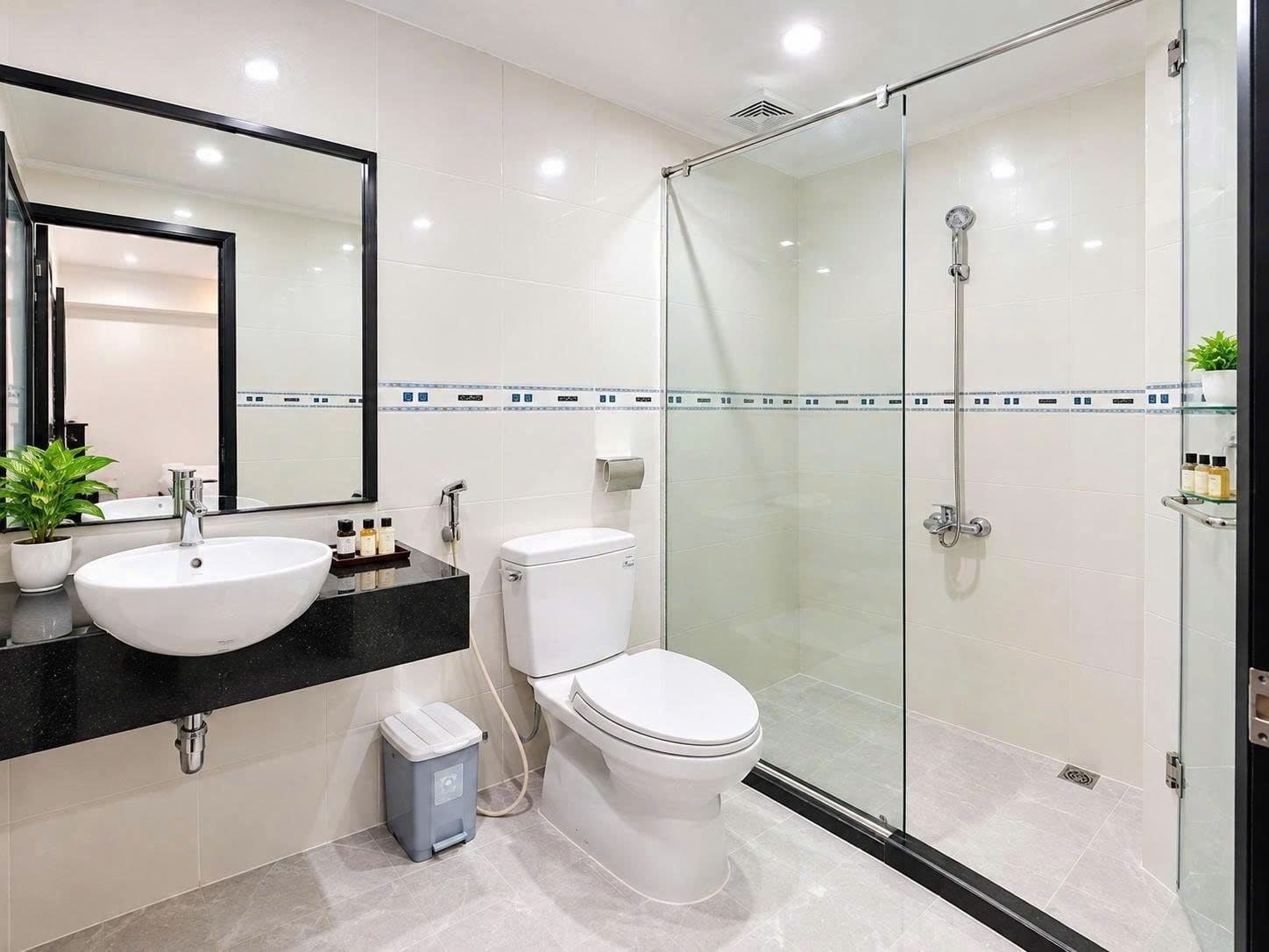 A modern bathroom with a glass-enclosed shower, a white toilet, and a sink with a black countertop.