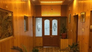 Un pasillo de madera con piso a cuadros, plantas en macetas y un aplique decorativo en el techo.