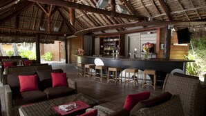 A covered outdoor seating area with wicker furniture and a bar.