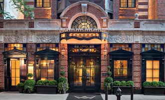 A hotel entrance with a classic brick facade, large arched windows, and a central entrance with a sign.