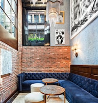 A cozy seating area with a blue sofa, two round tables, and a brick wall.
