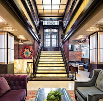 A grand staircase with a marble finish, leading to a dark wooden door.