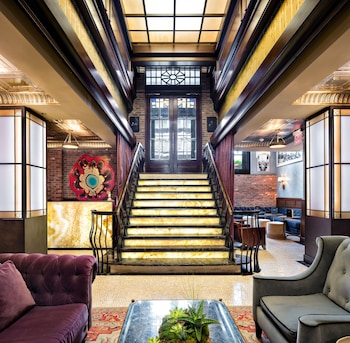 A cozy seating area with a blue sofa, two round tables, and a brick wall. at Walker Hotel Greenwich Village