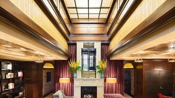 A spacious lobby with a high ceiling, a fireplace, seating area, and a bookshelf.