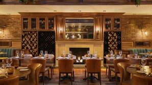 Een restaurant met een open haard, houten wanden en gedekte tafels.