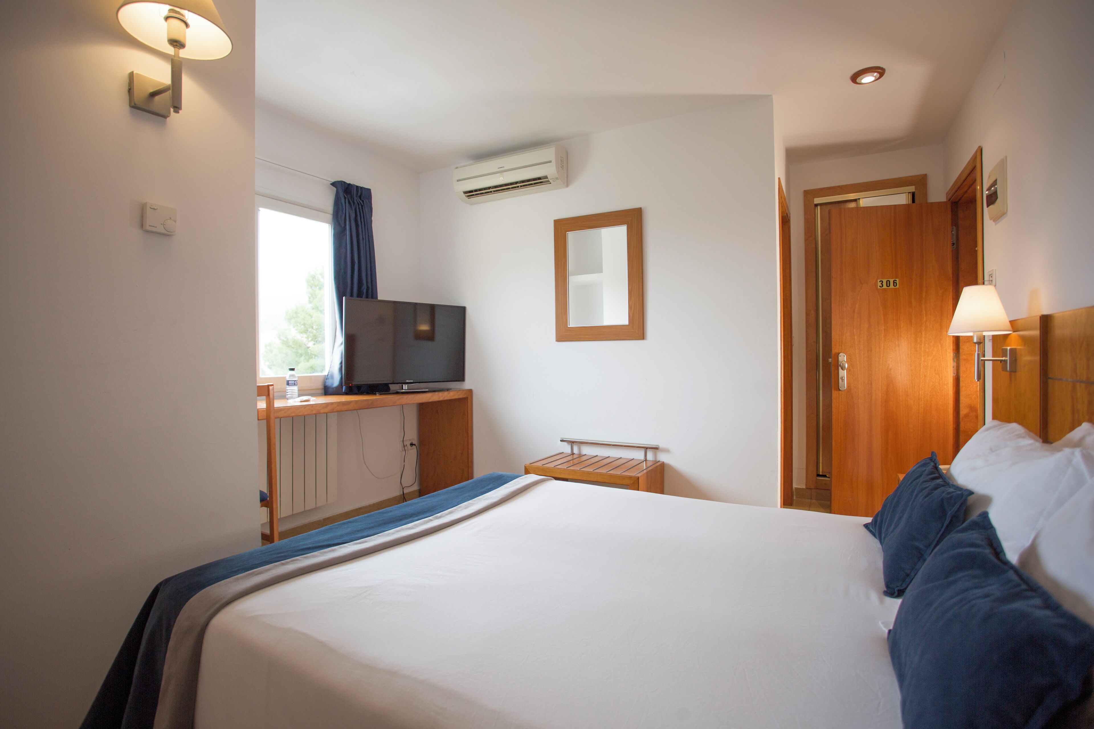 Una habitación de hotel con cama, televisión, escritorio y armario.
