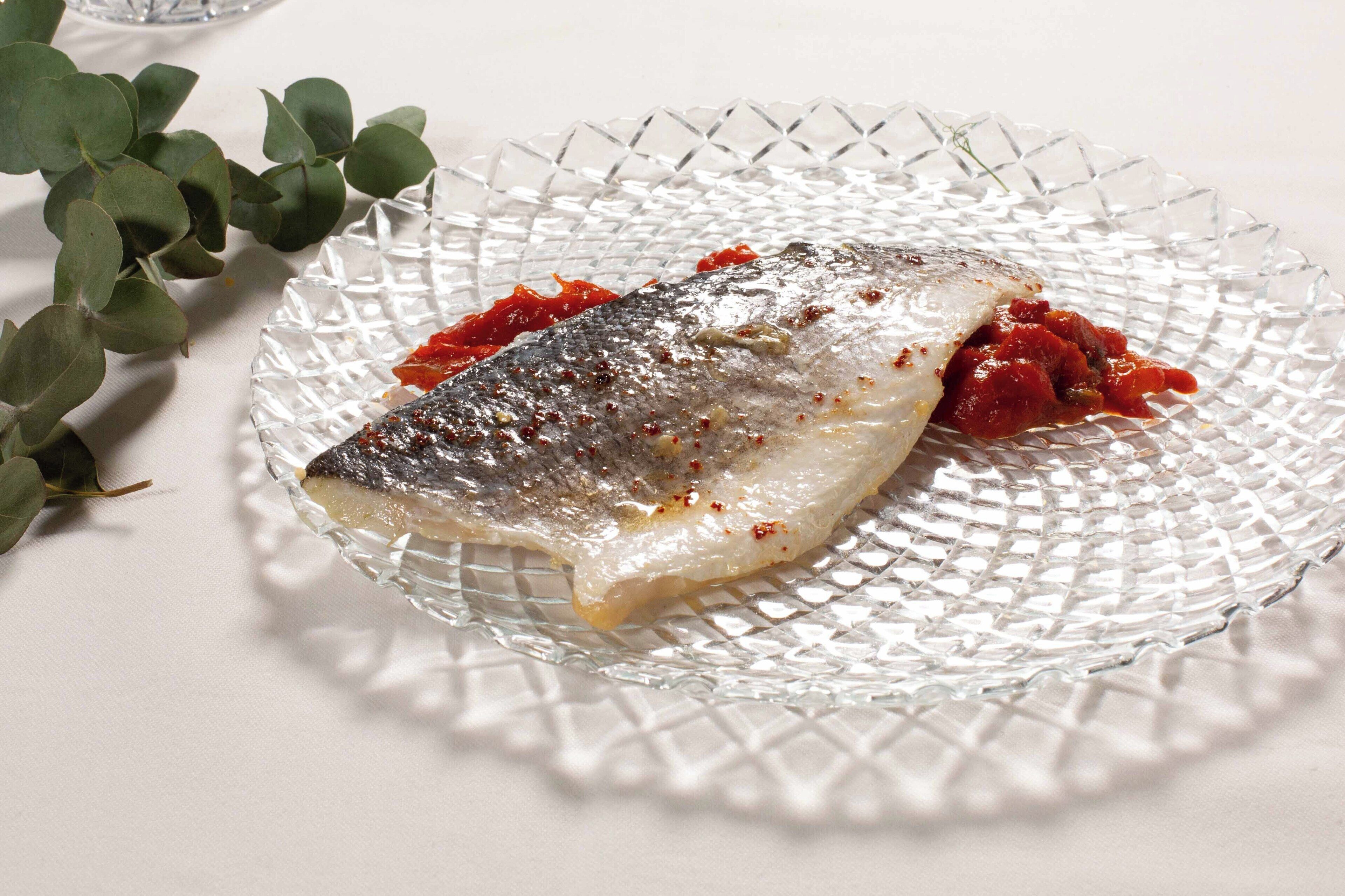 A glass plate with a fish and red sauce.