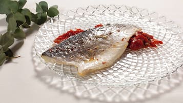 Un plato de vidrio con pescado y salsa roja.