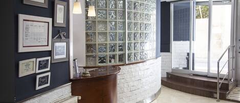 A reception area with a wooden counter, framed certificates on the wall, and a large glass window.