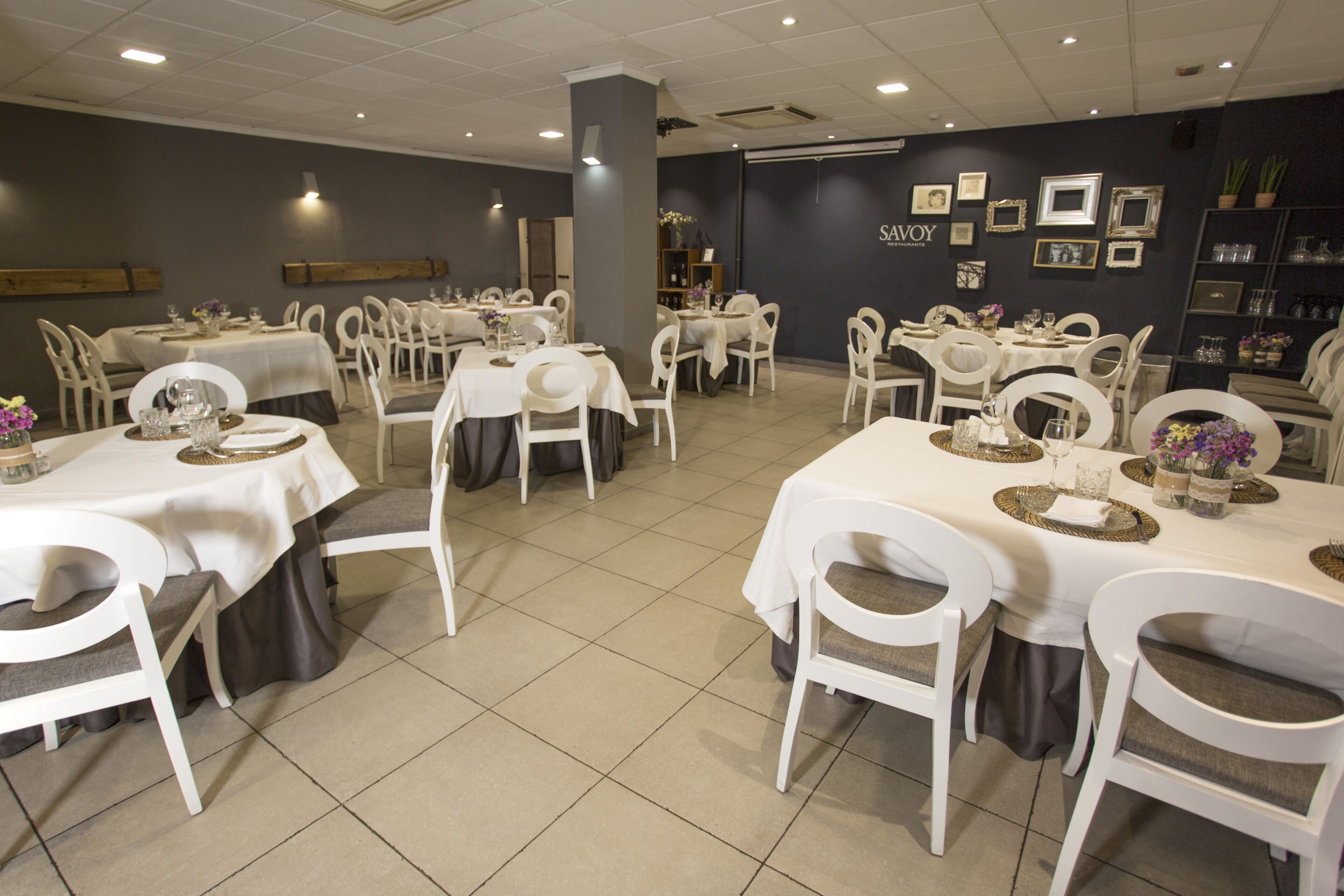 Un restaurante con varias mesas y sillas, cada juego con manteles blancos y cubertería.