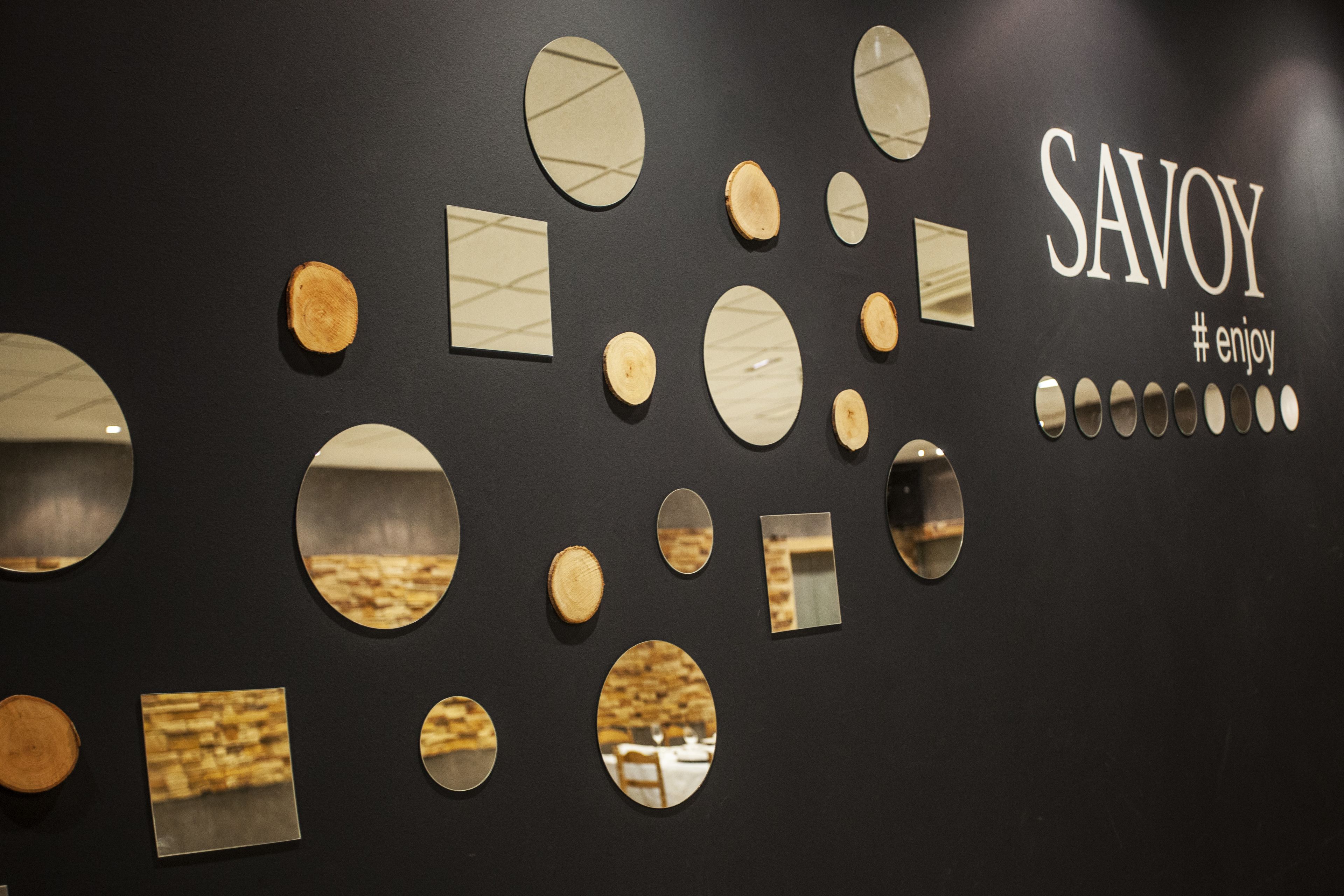 A wall with various circular mirrors and rectangular mirrors arranged in a pattern.