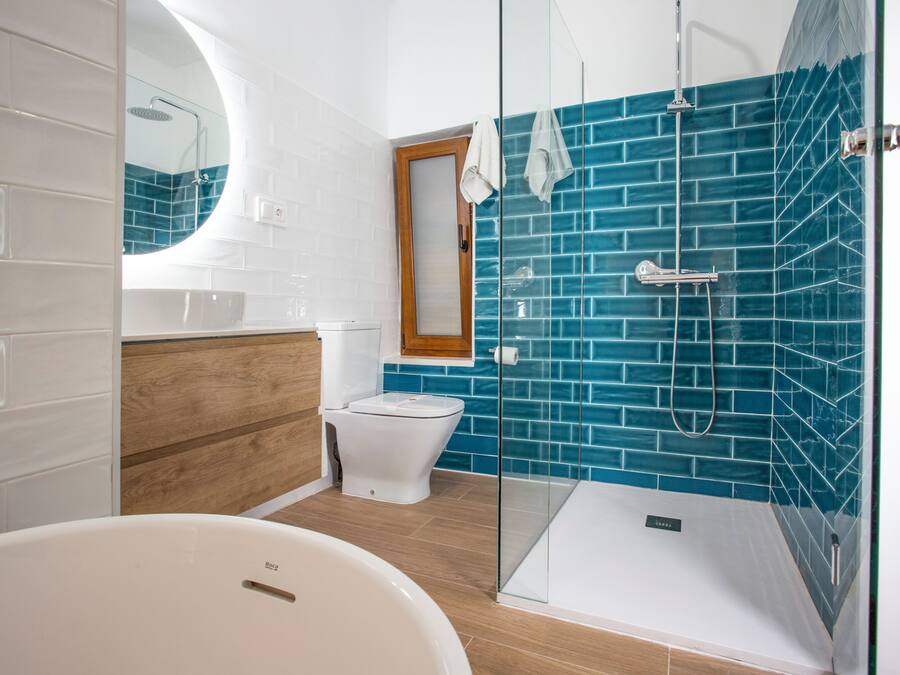 A modern bathroom with a glass-enclosed shower, a white bathtub, and a wooden vanity.