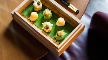 Un plateau en bois contenant des aliments, posé sur une feuille verte, lui-même placé sur une table.