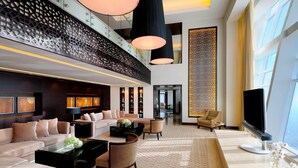 A spacious lobby with a modern sofa set, a coffee table, and a TV. - JW Marriott Marquis Hotel Dubai (Dubai)