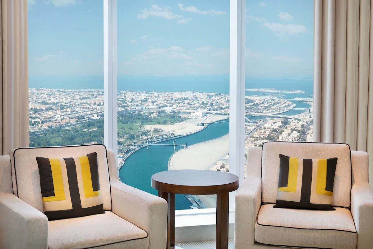 A high-rise hotel room with a view of a coastal cityscape, including a bridge and beach.