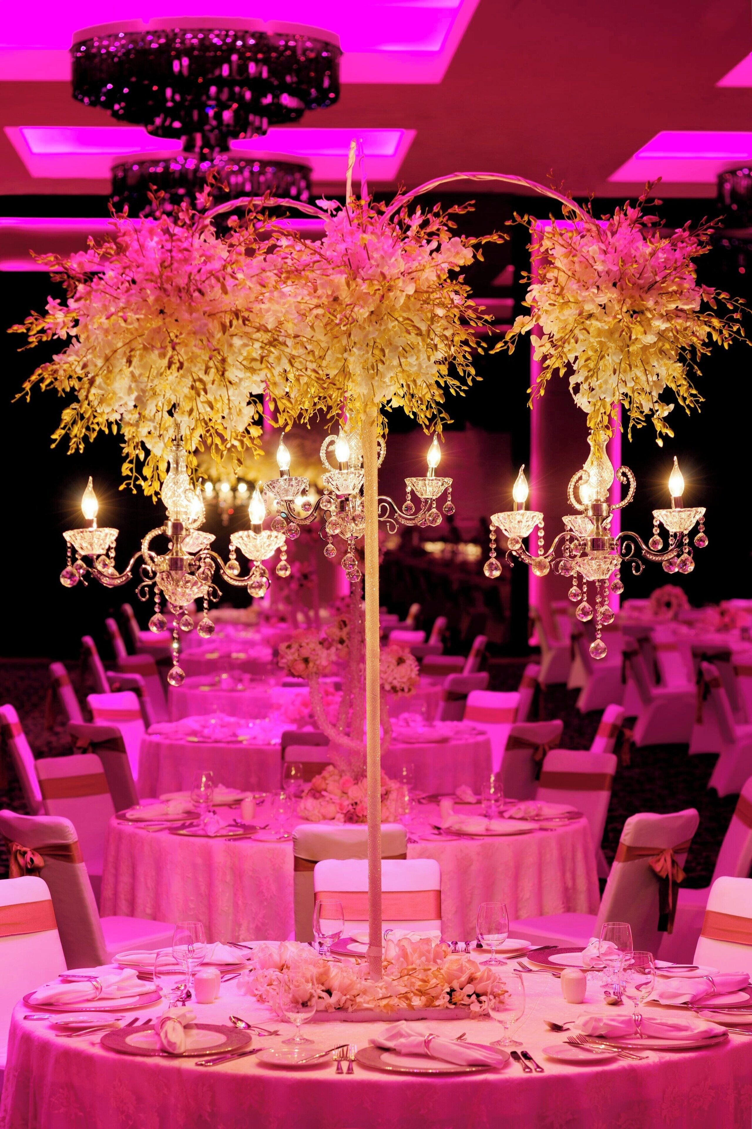 A banquet hall with round tables, each set with white tablecloths and floral centerpieces.