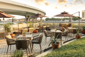An outdoor seating area with tables and chairs, umbrellas, and potted plants. - JW Marriott Marquis Hotel Dubai (Dubai)